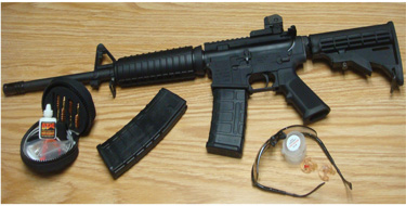 The economy rifle, complete with favored accessories – MagPul Pmags, shooting glasses, Surefire Sonic Defender earplugs, and OTIS Tactical cleaning kit. All that is now needed is a pony and tactical mane comber.