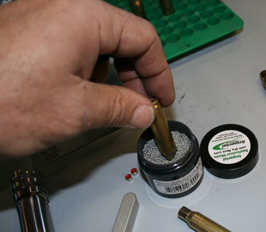 The container of tiny balls hold the dry lubricant to apply on the case necks. Poke the neck in and give a couple twists and the lube is transmitted to the neck.