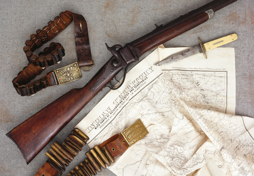 SellingGunts-17 Converted by a gunsmith in Montana Territory c. 1870s. Standard Sharps Civil War cavalry issue carbine altered to a classic style “Buffalo Rifle” by A. B. Charpie of Helena, Montana Territory, whose name and markings appear on the heavyweight 24-inch octagon barrel; caliber 50 centerfire; overall weight 11-1/2 lbs. Illustrated here with a Sheffield, England-made Bowie knife of the same era made for and bearing the markings of the well-known Denver, Colorado gunsmith and arms merchant John P. Lower & Son; also leather cartridge belts bearing brass buckles sold by Lower and the equally noted Denver gunsmiths and arms dealers Carlos Gove & Sons. (As illustrated in The Peacemakers; Arms and Adventure in the American West, with author’s permission)