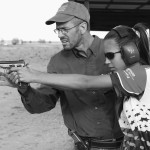 A father pressing the trigger for his daughter to eliminate shooter flinch. He is also able to check for her accuracy of aiming this way.