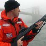 A U.S. Coast Guard petty officer from Maritime Safety and Security Team 91106 armed with an M870P fitted with a Trijicon reflex sight and a Speedfeed stock.