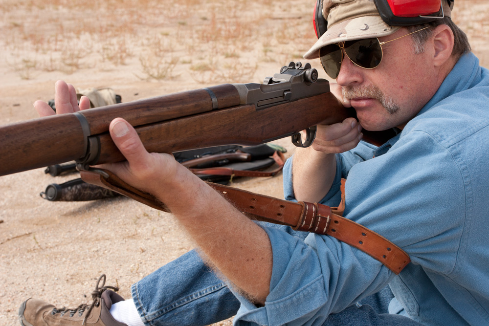 In sitting position with support forearm wrapped around sling and hand between sling and stock and wedged against front swivel.