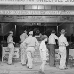A carnival shooting gallery from the 1940s. Note the signage about learning to shoot and defending yourself and your country. Hard to come by those sentiments these days.